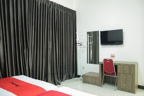 A hotel room with a bed, a desk, a chair, a television, and a wardrobe. - RedDoorz near GOR Satria Purwokerto (Purwokerto)