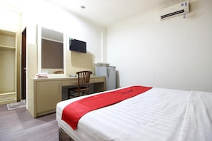 Een hotelkamer met een bed, een bureau met stoel, een televisie en een koelkast.