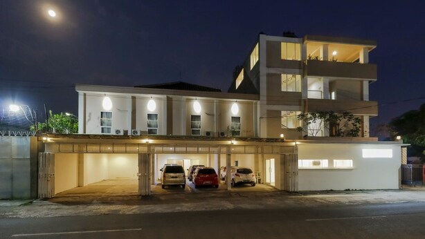 A modern multi-story building with a covered parking area and several cars parked inside. - RedDoorz near Stadion Manahan Solo (Surakarta)