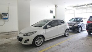A white car parked in a garage with a yellow line on the floor. - RedDoorz near Stadion Manahan Solo (Surakarta)