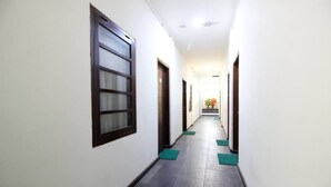 A long, narrow hallway with white walls and dark flooring. - RedDoorz near Stadion Manahan Solo (Surakarta)