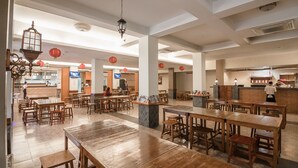 Un restaurant spacieux avec des tables et des chaises en bois, un comptoir et des lanternes rouges.