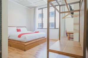 A modern hotel room with a wooden bed, a desk, and a large window. - RedDoorz Plus near Soekarno Hatta Airport 2 (Tangerang)