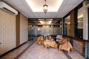 A lobby with a patterned carpet, a ceiling light fixture, and a sign indicating a coffee shop. - RedDoorz Plus near Soekarno Hatta Airport 2 (Tangerang)