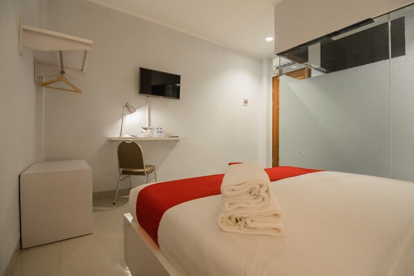 A hotel room with a bed, a desk, a chair, a TV, and a wardrobe. - RedDoorz Plus near Soekarno Hatta Airport 2 (Tangerang)