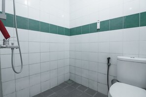A small, tiled bathroom with a shower, toilet, and a green stripe on the wall. - RedDoorz @ Buah Batu 3 (Bandung)
