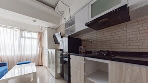 Een moderne keuken met een ingebouwde oven, een magnetron en een kookplaat. Er is een eethoek met een witte tafel en blauwe stoelen.