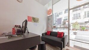 Een moderne kantoorruimte met een receptiebalie, een zwarte bank met rode kussens en een groot raam met uitzicht op de straat.