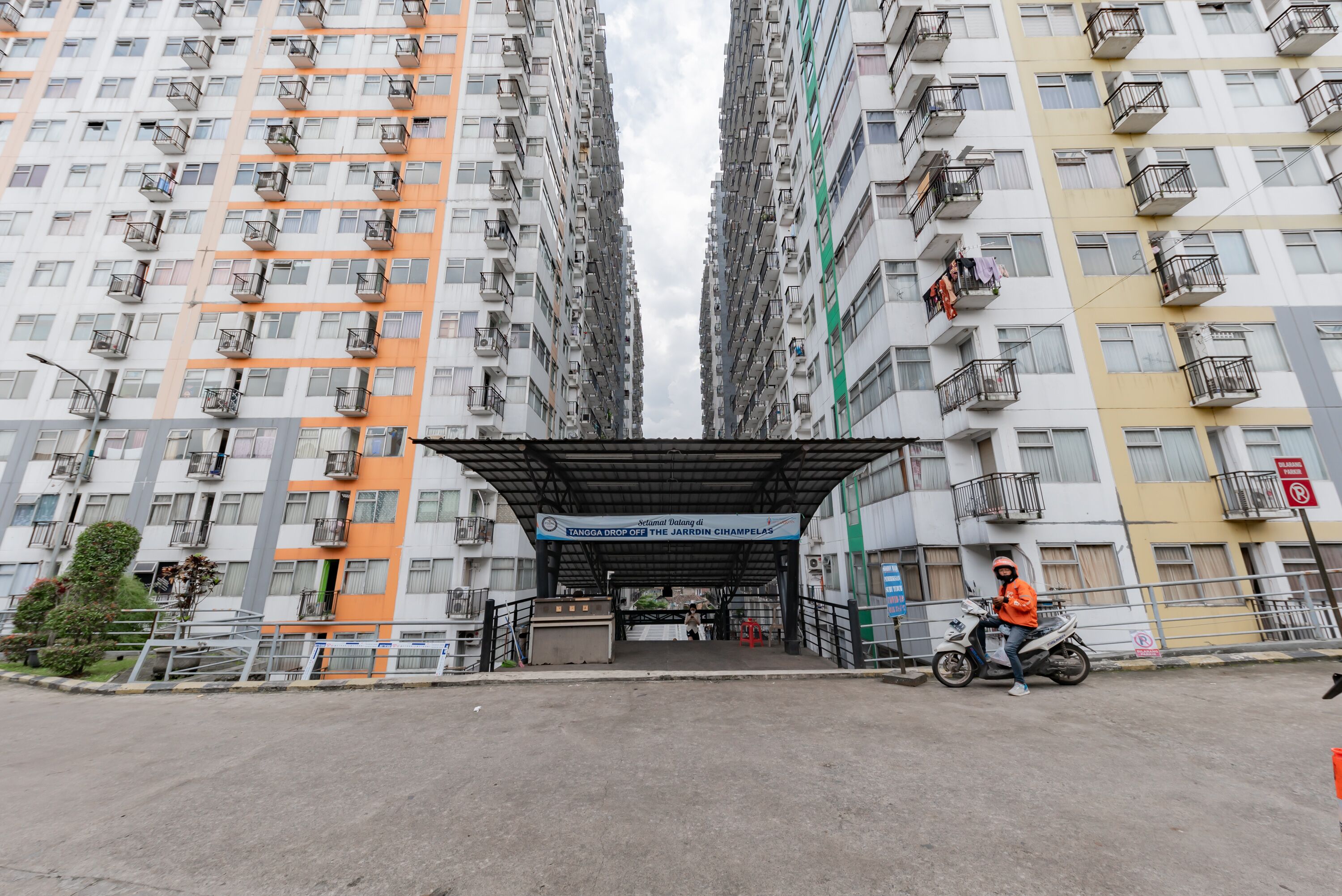 Un edificio residencial de gran altura con balcones y un acceso cubierto.