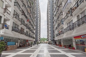 Een hoog appartementencomplex met balkons, een centrale binnentuin en winkels op de begane grond.
