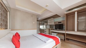 Een moderne hotelkamer met een bed, een bureau, een televisie en een kledingkast.