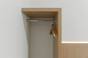 A corner of a room with a wooden shelf, a metal towel rack, and a hanging towel. - RedDoorz near Mall SKA Pekanbaru (Pekanbaru)