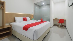 A modern hotel room with a large bed, a desk, and a shower area. - RedDoorz near Mall SKA Pekanbaru (Pekanbaru)