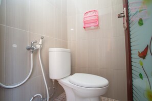 Une salle de bain avec des toilettes, une douche et un panier rose accroché au mur.