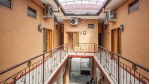 Un interior de varios niveles con una escalera central, unidades de aire acondicionado y un techo de azulejos.