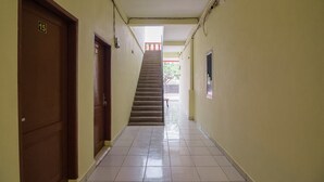 A hallway with a staircase leading to an upper floor, a door labeled '15', and a poster on the wall. - RedDoorz near Politeknik Negeri Medan (Medan)