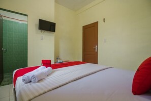 A hotel room with a bed, a TV mounted on the wall, a shower area, and a door. - RedDoorz near Politeknik Negeri Medan (Medan)