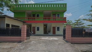 A two-story building with a green and red facade, a balcony, and a gated entrance. - RedDoorz near Politeknik Negeri Medan (Medan)