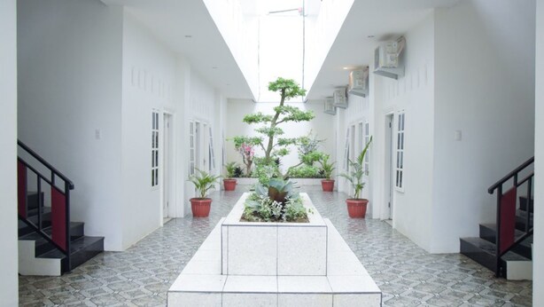 Ein modernes Interieur mit einem zentralen Garten, weißen Wänden und einem gefliesten Boden.