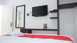 Ein Hotelzimmer mit Bett, Wandfernseher, Kleiderschrank und Tür.