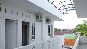 Ein weißes Gebäude mit mehreren Fenstern und Türen, Klimaanlagen und einem Balkon mit Metallgeländer.