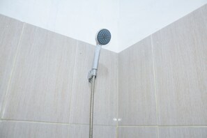 Ducha con cabezal de ducha manual en un baño con azulejos.
