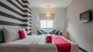 Ein Hotelzimmer mit einem Bett, zwei Stühlen, einem Fernseher und einem Fenster.