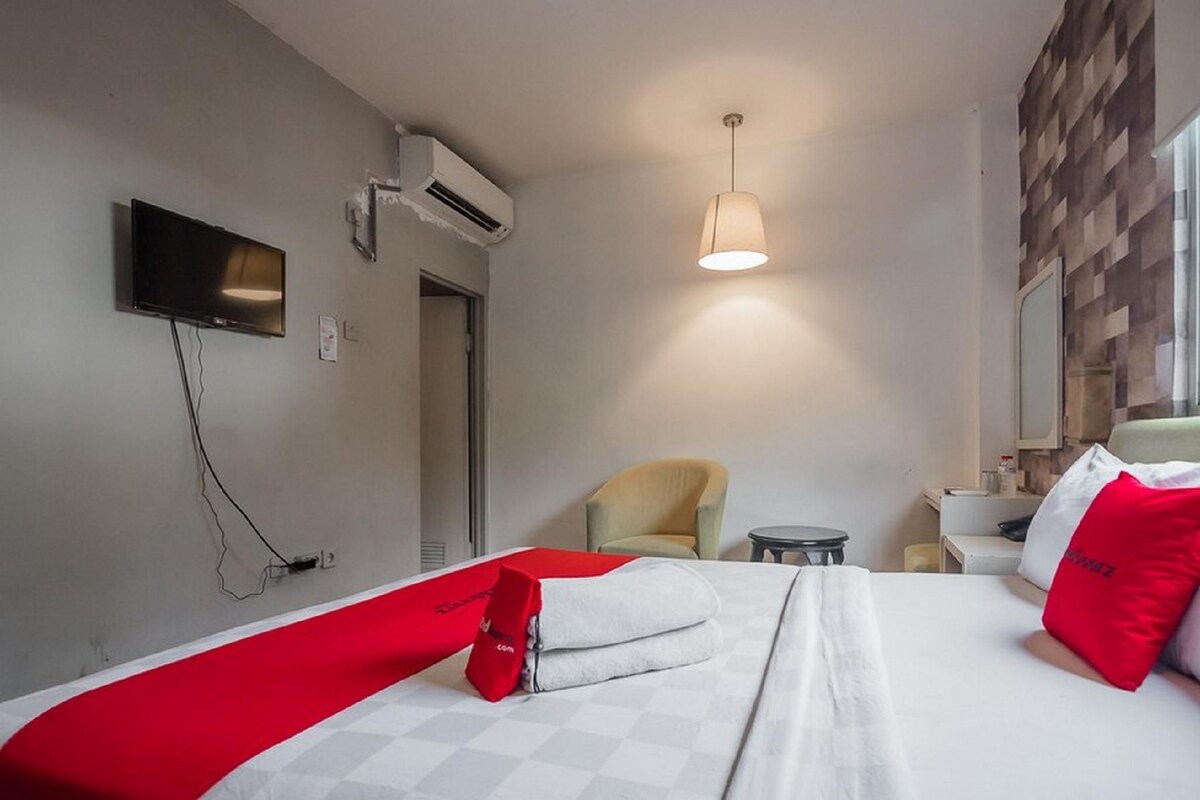 A hotel room with a bed, a chair, a desk, and a television.