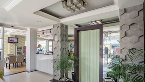 Eine moderne Lobby mit einer Rezeption, einer Sitzecke und einer großen Pflanze in einem Topf.