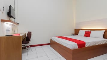 A bedroom with a wooden bed, a desk with a chair, a TV mounted on the wall, and a bedside table.