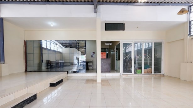 A spacious, well-lit interior with a tiled floor, a staircase, and a glass door leading to another area. - RedDoorz @ Jalan Setiabudi Semarang (Semarang)