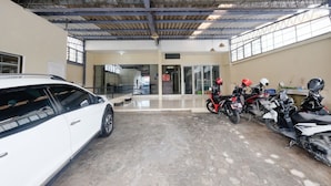 A spacious indoor parking area with a white car and several motorcycles. - RedDoorz @ Jalan Setiabudi Semarang (Semarang)