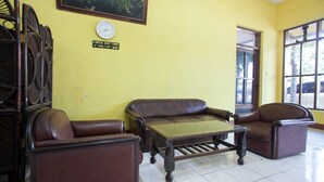 A yellow-walled room with a brown leather sofa, a wooden coffee table, and wicker chairs.