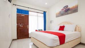 A hotel room with a bed, a window with curtains, a door, and a painting on the wall.