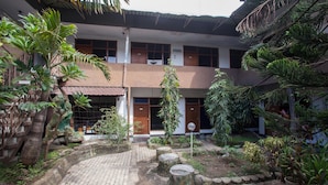 A courtyard with a brick pathway, wooden stumps, and various tropical plants.