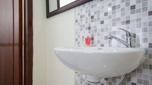 A bathroom with a white sink, a mirror above it, and a tiled backsplash.