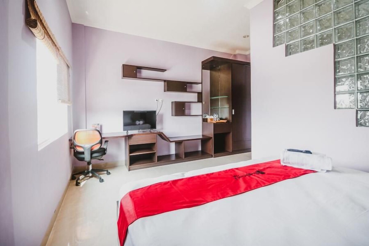 A modern hotel room with a bed, a desk, and a TV.