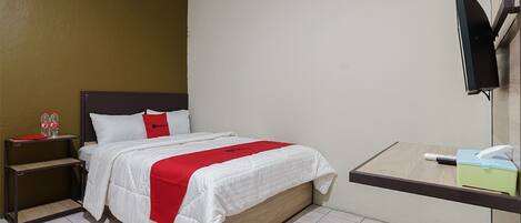 Ein Hotelzimmer mit Bett, Nachttisch, Fernseher und Schreibtisch mit Stuhl.