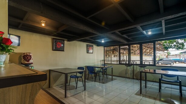 A restaurant with a wooden counter, blue chairs, and a tiled floor. - RedDoorz near Cikampek Mall Karawang (Karawang)