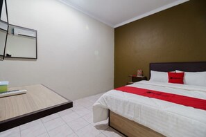 A hotel room with a bed, a bedside table, a nightstand, and a mirror. - RedDoorz near Cikampek Mall Karawang (Karawang)
