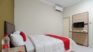 A hotel room with a bed, a TV mounted on the wall, and a wooden desk. - RedDoorz near Cikampek Mall Karawang (Karawang)