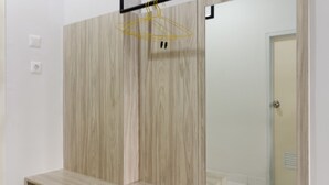 A modern bathroom with wooden paneling, a mirror, and a hanging clothes rack. - RedDoorz Apartment @ Dramaga Tower (Ciampia)