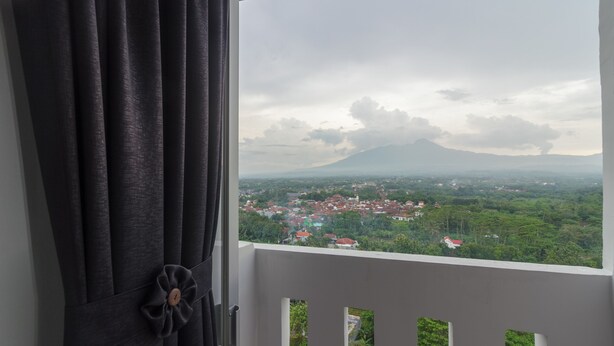 A balcony with a view of a town and a mountain. - RedDoorz Apartment @ Dramaga Tower (Ciampia)