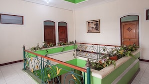 A hotel lobby with a green and white color scheme, a central staircase, and wooden doors. - RedDoorz @ Genteng Surabaya 2 (Surabaya)