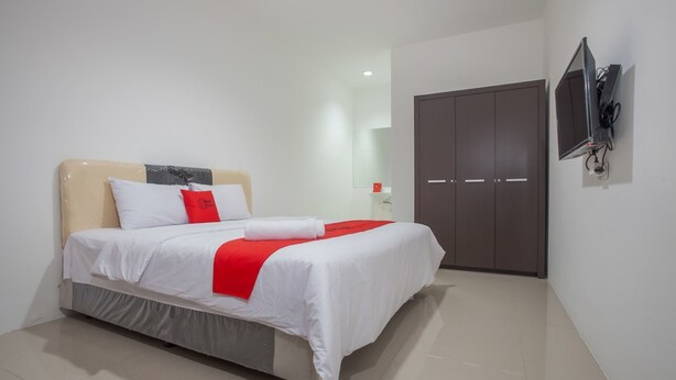 Ein modernes Hotelzimmer mit einem Bett, einem Kleiderschrank und einem an der Wand befestigten Fernseher.