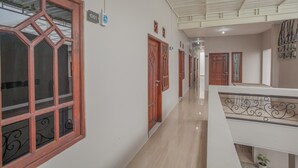 A corridor with wooden doors and a tiled floor. - RedDoorz near Ciputra Golf Surabaya (Surabaya)