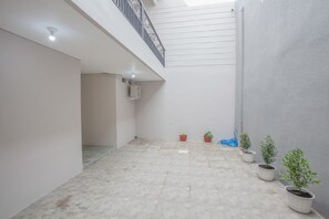 Un espace intérieur spacieux doté d’un sol carrelé, d’un balcon avec une balustrade et de plusieurs plantes en pot.
