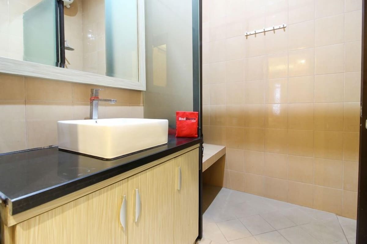 A modern bathroom with a white sink, black countertop, and light wood cabinets.