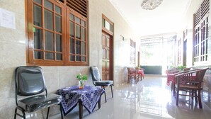 Um hall amplo com piso de azulejos, portas de madeira e uma área de estar com cadeiras e uma mesa.