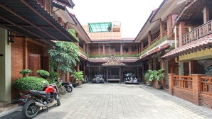 A courtyard with a paved walkway, potted plants, and parked motorcycles. - RedDoorz near AMIKOM Yogyakarta 2 (Depok)